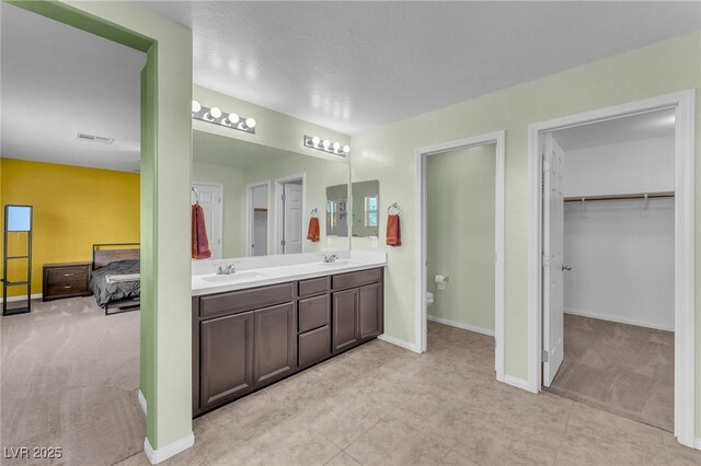 full bath featuring double vanity, visible vents, toilet, and a sink