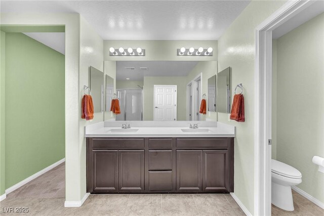 full bathroom featuring double vanity, a sink, toilet, and baseboards