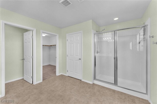 full bath with a walk in closet, visible vents, a shower stall, and baseboards