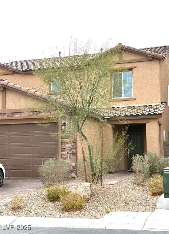 view of front facade featuring stucco siding, driveway, a tile roof, and an attached garage