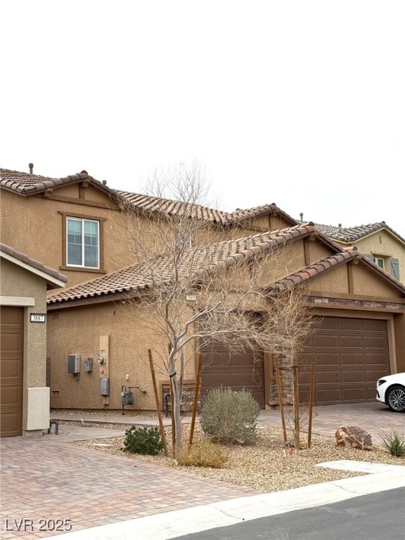 view of front of house featuring stucco siding, a tiled roof, decorative driveway, and a garage