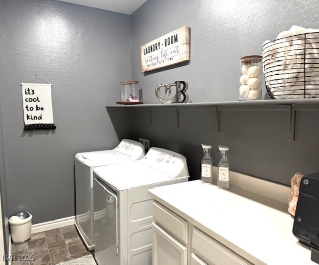 laundry area featuring washing machine and clothes dryer, cabinet space, stone finish floor, and baseboards