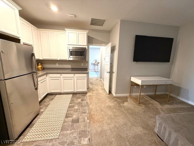 kitchen with stainless steel appliances, light carpet, visible vents, and white cabinets