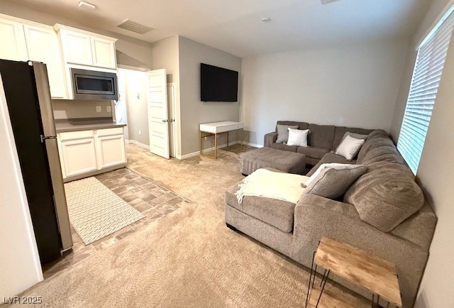 living area with light carpet, visible vents, and baseboards