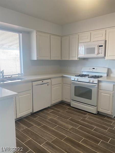 kitchen featuring wood finish floors, white appliances, white cabinetry, and a sink