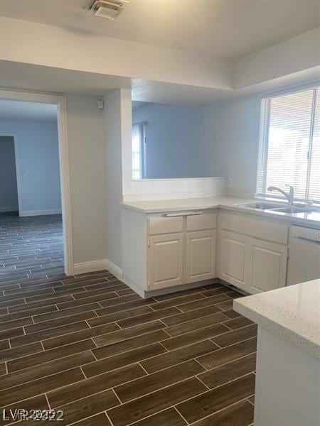 kitchen with visible vents, white cabinets, dishwasher, wood finish floors, and a sink