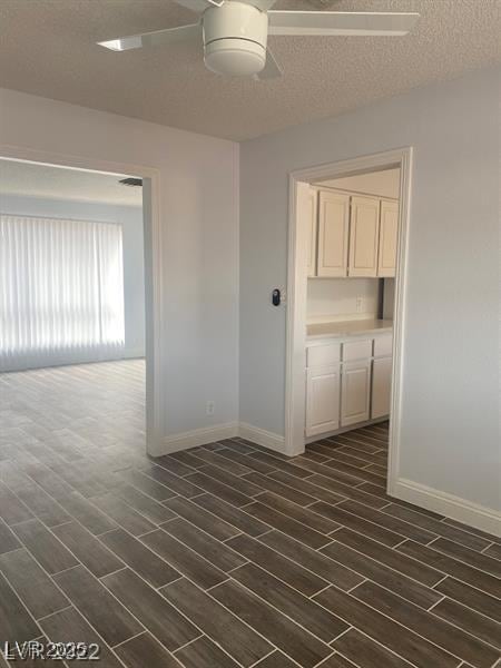 spare room with wood tiled floor, a textured ceiling, baseboards, and a ceiling fan