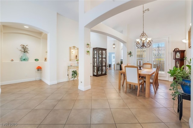 dining room with light tile patterned floors, baseboards, and a high ceiling