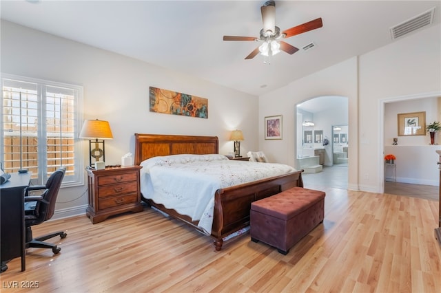 bedroom with baseboards, arched walkways, visible vents, and light wood-type flooring