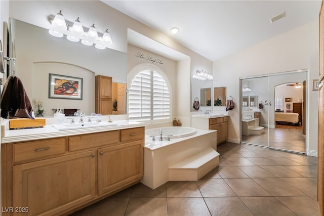 bathroom featuring tile patterned floors, a garden tub, lofted ceiling, and connected bathroom