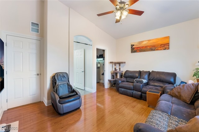 living room with baseboards, visible vents, high vaulted ceiling, light wood-style flooring, and ceiling fan