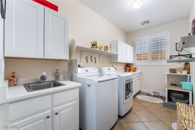 clothes washing area with visible vents, light tile patterned floors, washer and dryer, cabinet space, and a sink