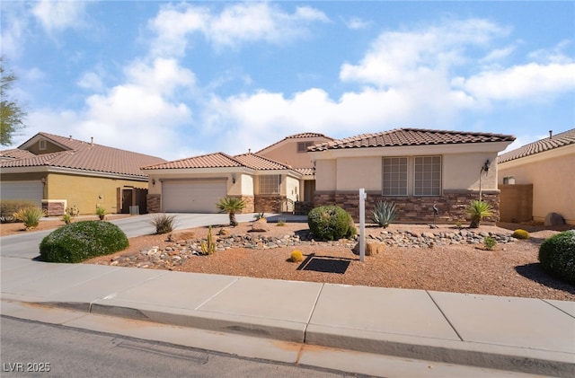 mediterranean / spanish-style home with a tiled roof, concrete driveway, stucco siding, stone siding, and an attached garage