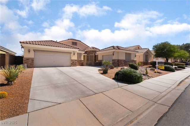 mediterranean / spanish house featuring stucco siding, stone siding, a garage, and concrete driveway