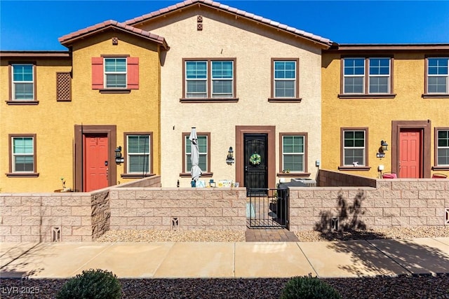 view of property featuring a fenced front yard, stucco siding, a tiled roof, and a gate