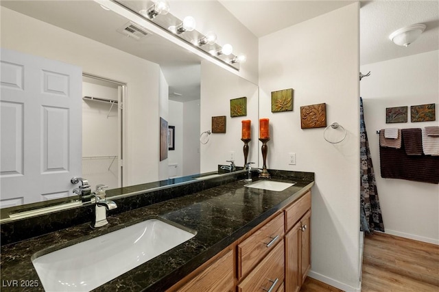 full bath with wood finished floors, a sink, visible vents, and baseboards