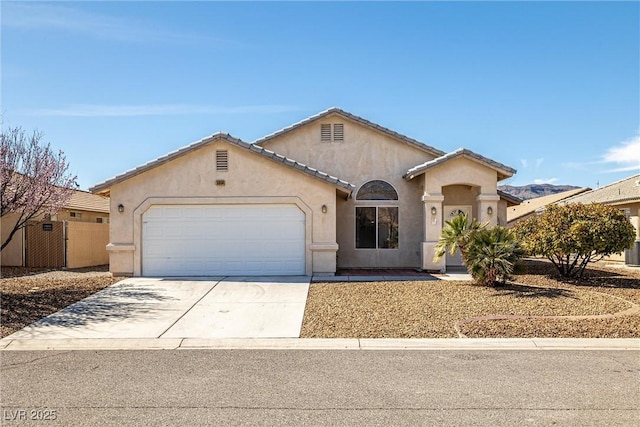 mediterranean / spanish-style home with driveway, an attached garage, a tiled roof, and stucco siding