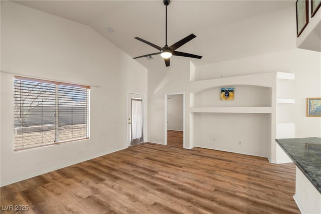 unfurnished living room with ceiling fan, high vaulted ceiling, and wood finished floors