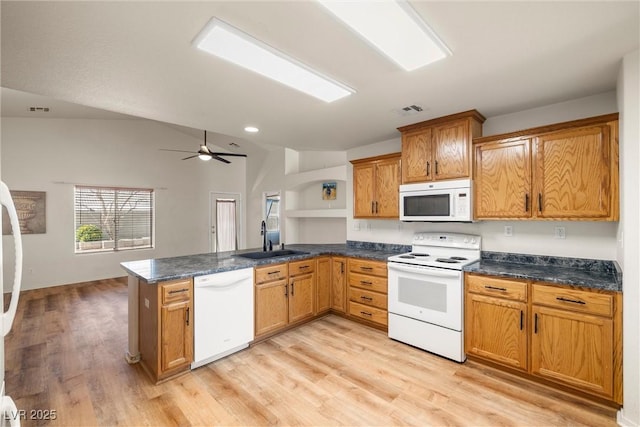 kitchen with white appliances, visible vents, dark countertops, a peninsula, and a sink