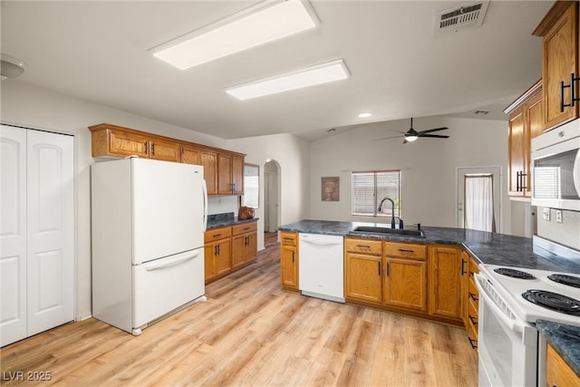 kitchen with arched walkways, brown cabinets, visible vents, a sink, and white appliances