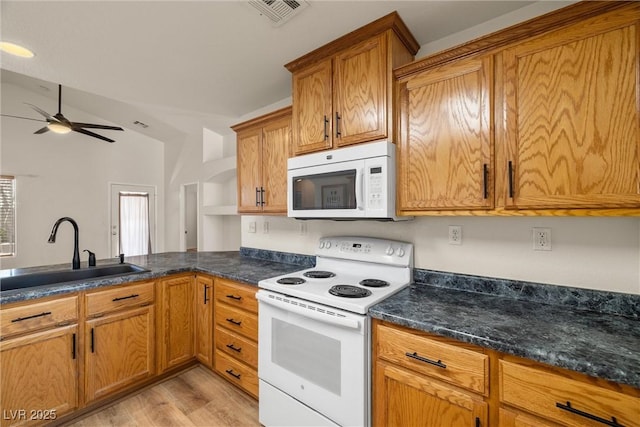 kitchen featuring white appliances, light wood finished floors, visible vents, brown cabinets, and a sink