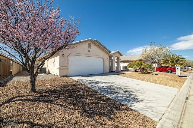 ranch-style house featuring a garage, concrete driveway, and stucco siding