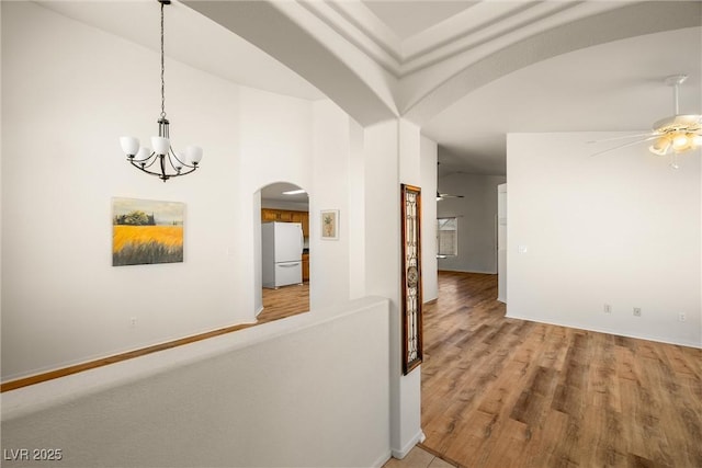 corridor with arched walkways, wood finished floors, and a notable chandelier