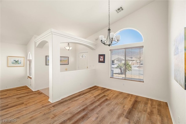 unfurnished dining area featuring high vaulted ceiling, visible vents, wood finished floors, a chandelier, and baseboards