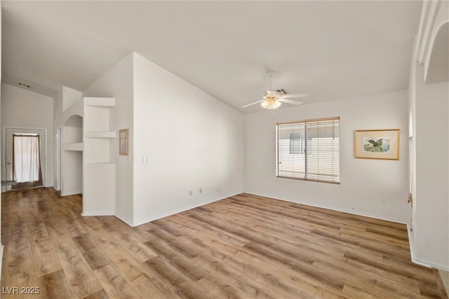 spare room featuring a ceiling fan, lofted ceiling, and light wood-style flooring