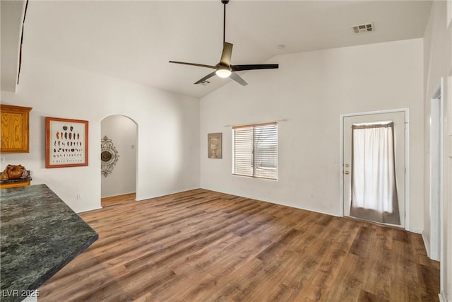 living area with arched walkways, wood finished floors, visible vents, and a ceiling fan