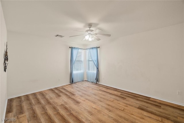 spare room with light wood-type flooring, ceiling fan, visible vents, and baseboards