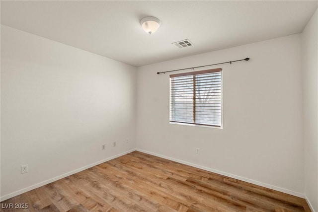 unfurnished room with visible vents, light wood-style flooring, and baseboards