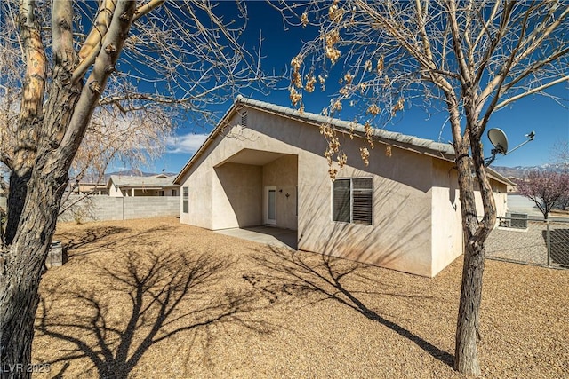 back of property featuring fence and stucco siding