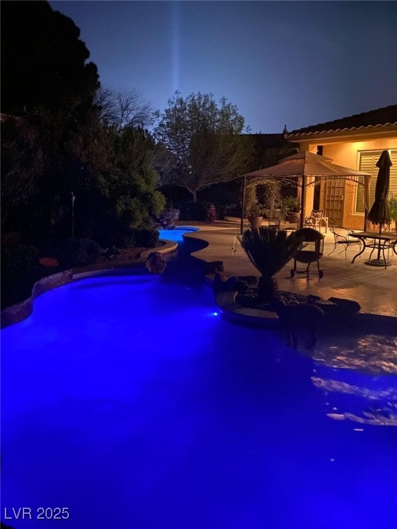 pool at twilight featuring an outdoor pool and a patio area