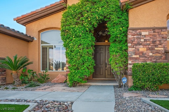 doorway to property with a tile roof and stucco siding