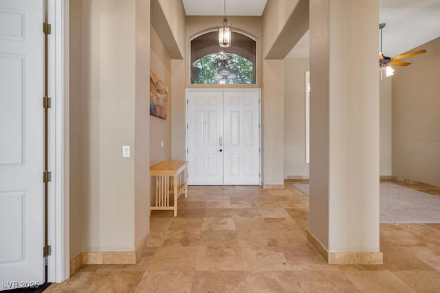 entrance foyer featuring baseboards, a high ceiling, and ceiling fan