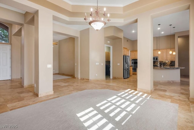 interior space with a chandelier, baseboards, a raised ceiling, and a towering ceiling