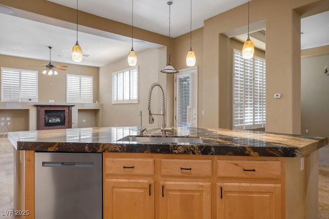 kitchen featuring light brown cabinets, a sink, a glass covered fireplace, dishwasher, and ceiling fan