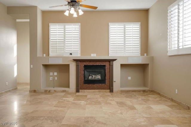 unfurnished living room featuring a fireplace, baseboards, and ceiling fan