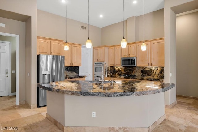 kitchen featuring dark stone counters, light brown cabinetry, decorative backsplash, a towering ceiling, and appliances with stainless steel finishes