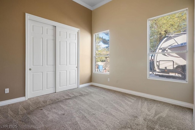 unfurnished bedroom featuring a closet, baseboards, carpet flooring, and crown molding