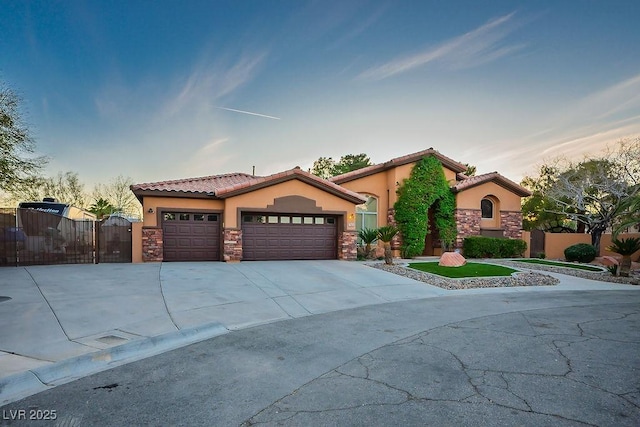 mediterranean / spanish-style house featuring fence, driveway, stucco siding, a garage, and stone siding