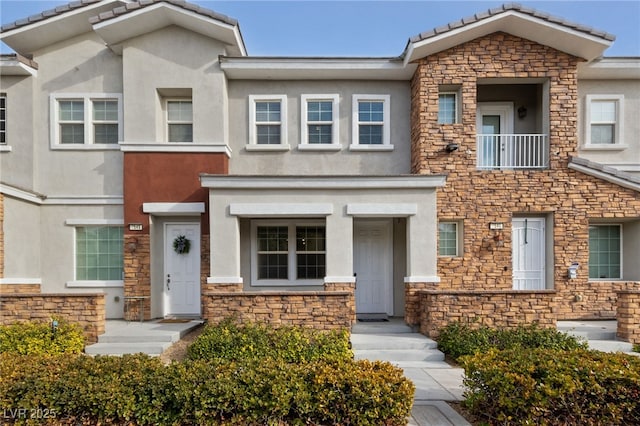 multi unit property with stone siding, a tiled roof, and stucco siding