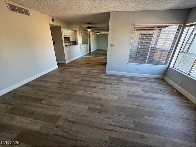 empty room featuring visible vents, dark wood-type flooring, and a textured ceiling