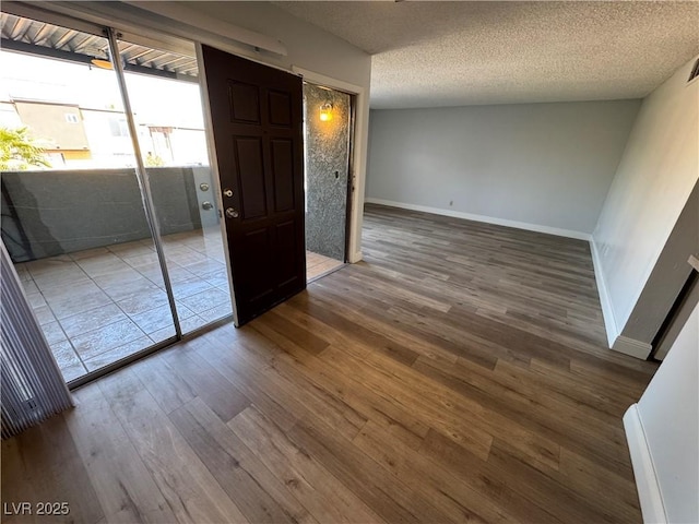 empty room featuring visible vents, a textured ceiling, baseboards, and wood finished floors