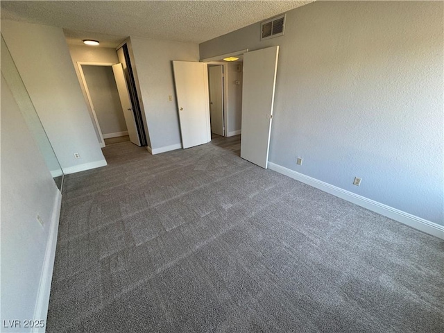 unfurnished bedroom with baseboards, a textured ceiling, visible vents, and carpet flooring