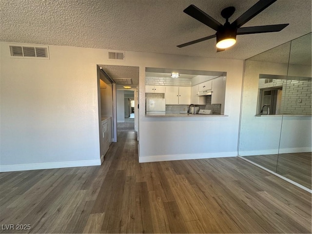 kitchen featuring dark wood-style floors, visible vents, white fridge, and tasteful backsplash