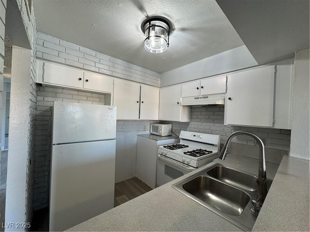 kitchen with white appliances, a sink, white cabinetry, and under cabinet range hood