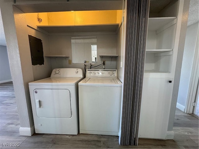 washroom featuring wood finished floors, separate washer and dryer, laundry area, electric panel, and baseboards