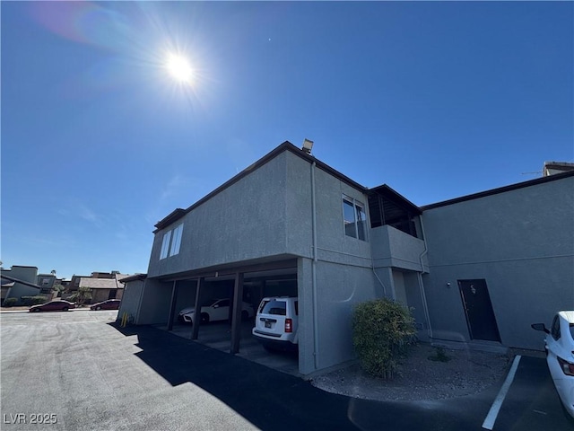 view of home's exterior featuring stucco siding and covered and uncovered parking